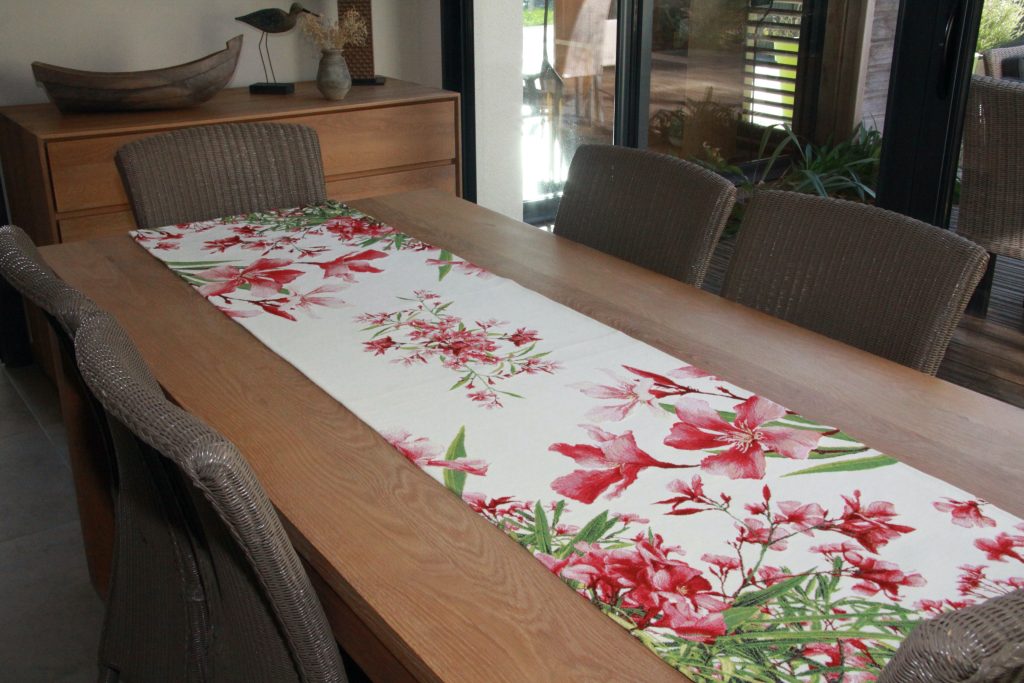 Chemin de table fleuri aux motifs rouges, disposé sur une table en bois.