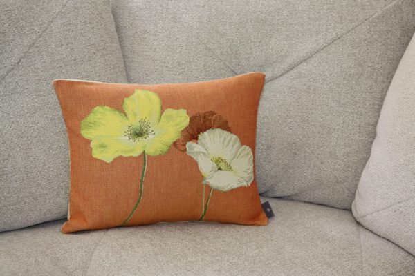 Coussin décoratif aux fleurs brodées sur fond orange, conçu en tissu jacquard par des artisans français.