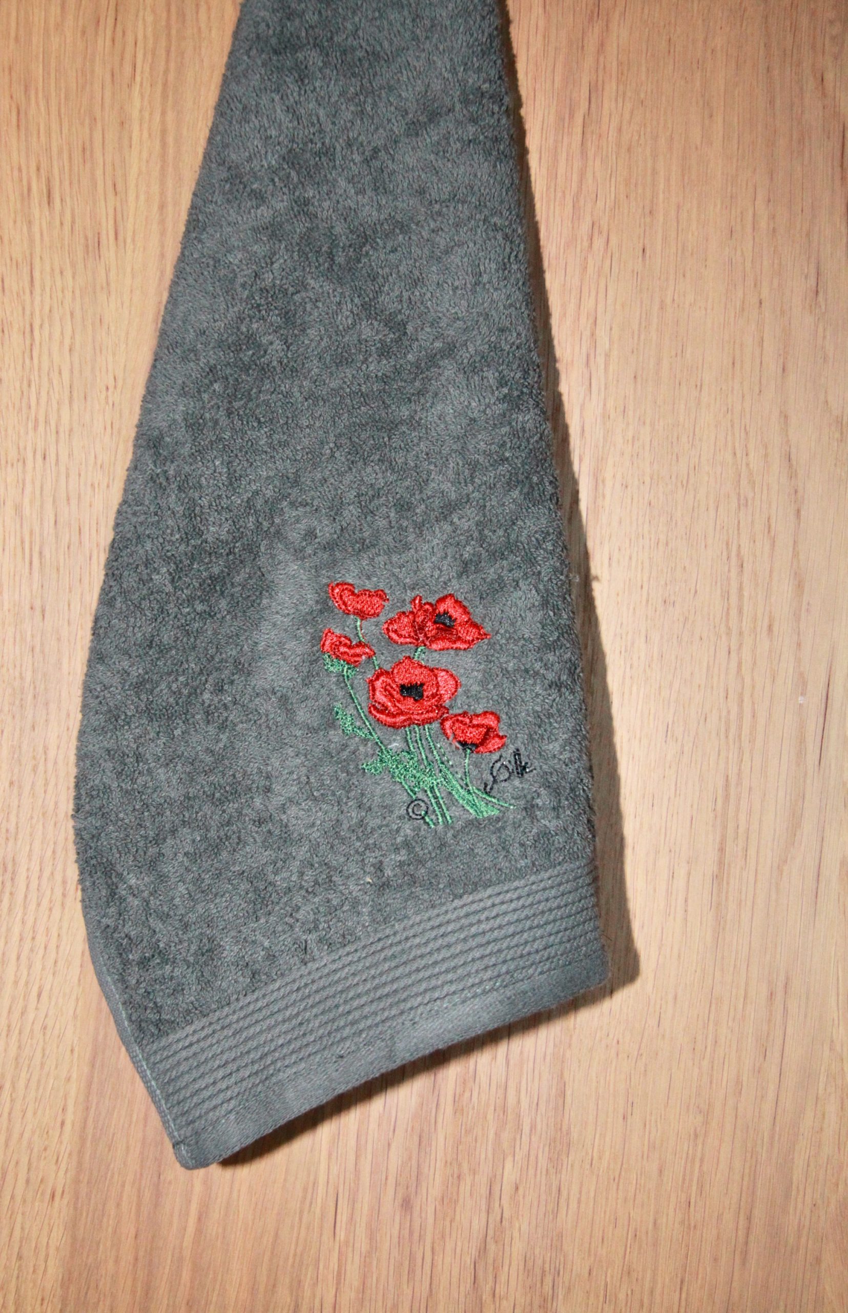Serviette invité grise avec broderie de coquelicots, fabriquée en France, issue de la boutique Poppies Shop à Bayeux.