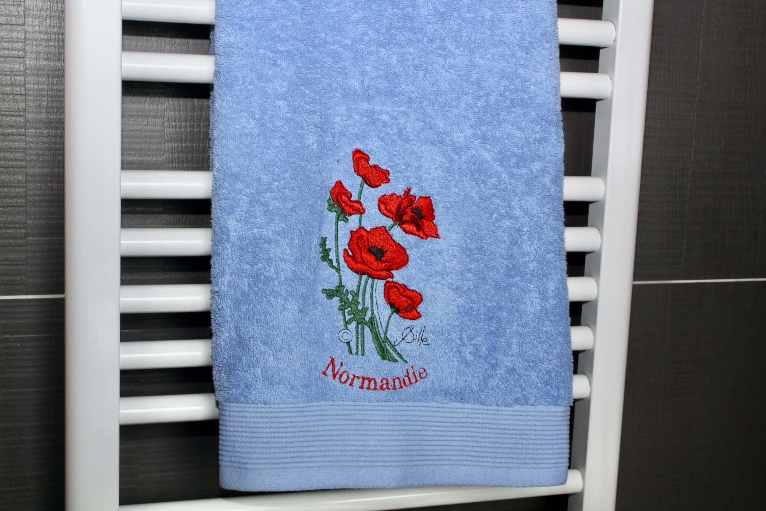 Blue bath towel with poppy embroidery and the inscription "Normandie".