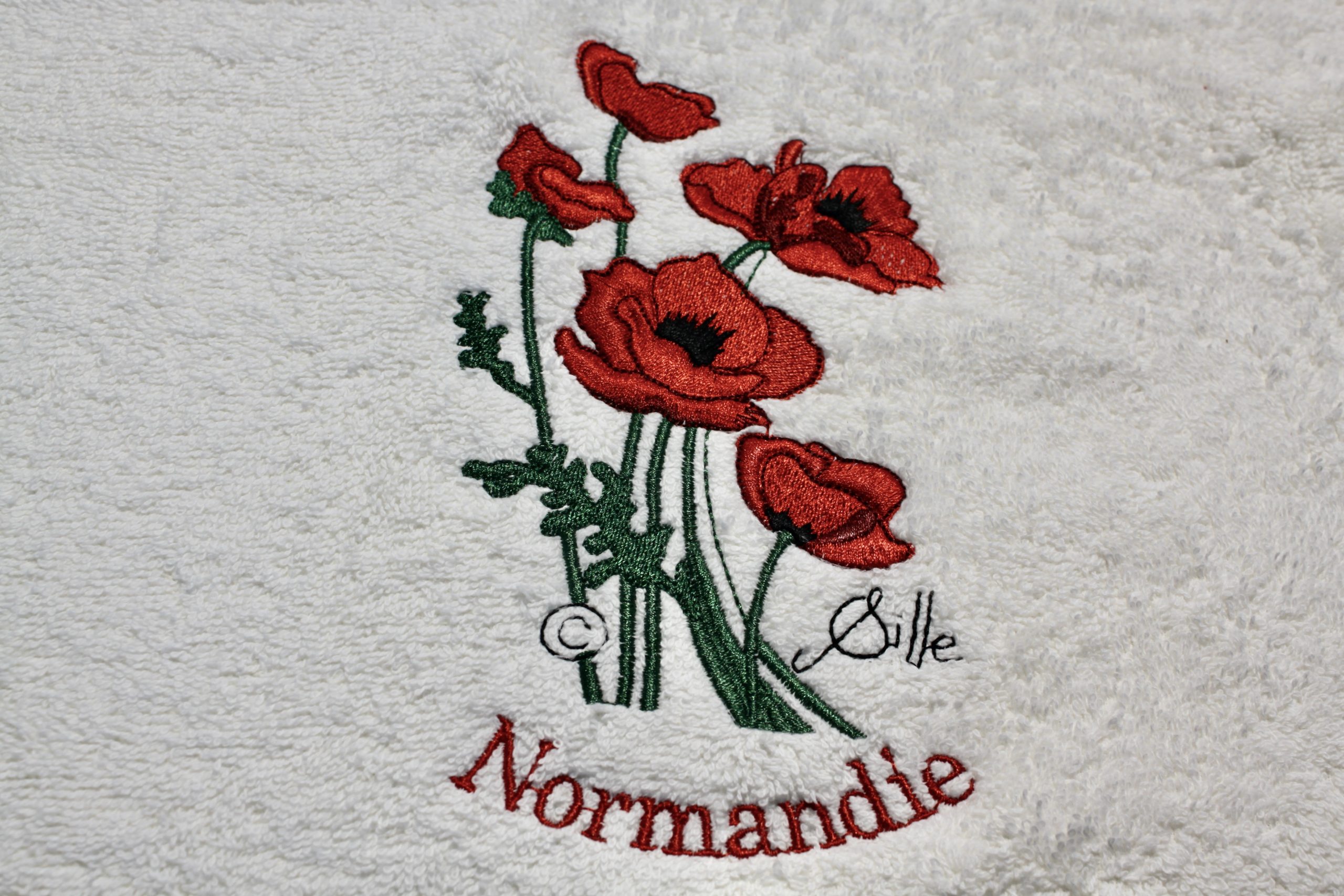 White bath towel with red poppy embroidery and the inscription "Normandie".