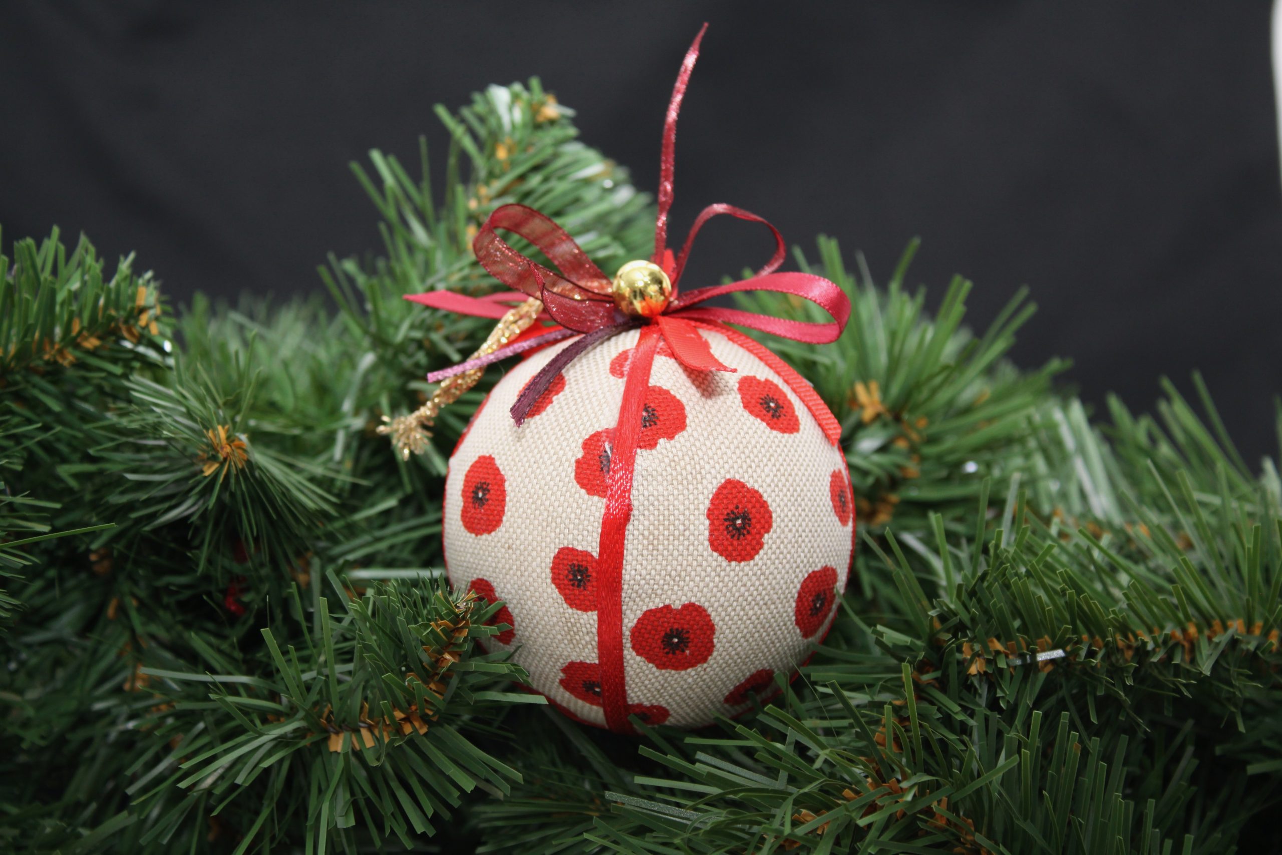 Boule de Noël en tissu crème ornée de coquelicots rouges, avec un ruban. Décoration originale pour les fêtes.