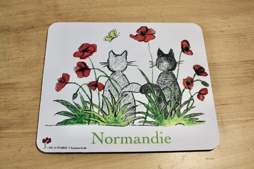 Tapis de souris illustré de deux chats dans un champ de coquelicots, avec le mot "Normandie" en bas.
