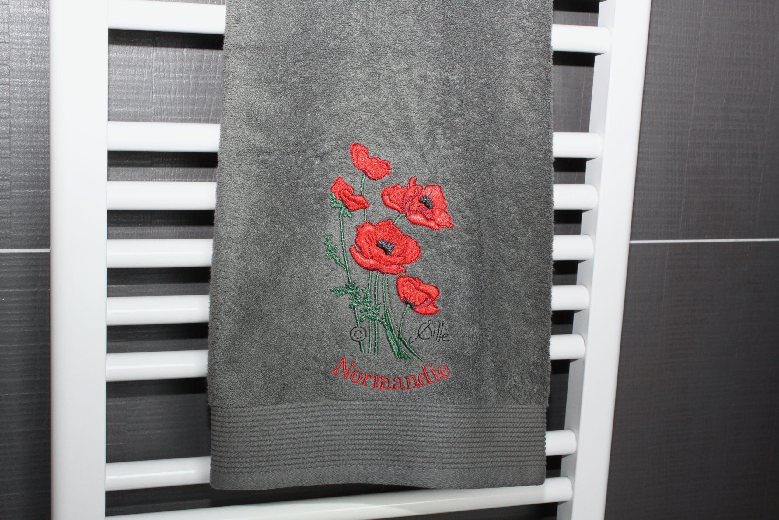 Grey bath towel with embroidered red poppies and the inscription "Normandie". Handmade by Poppies Shop, Bayeux.