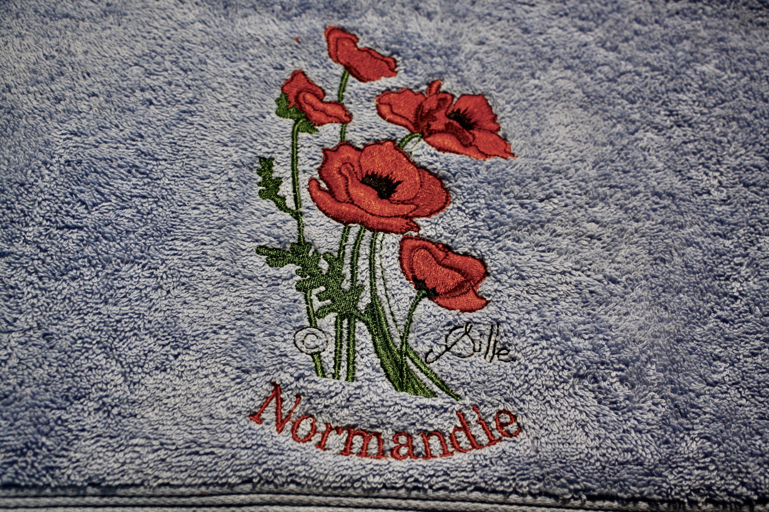 Towel with poppy embroidery and the inscription "Normandie". Design by the artist Sqille.