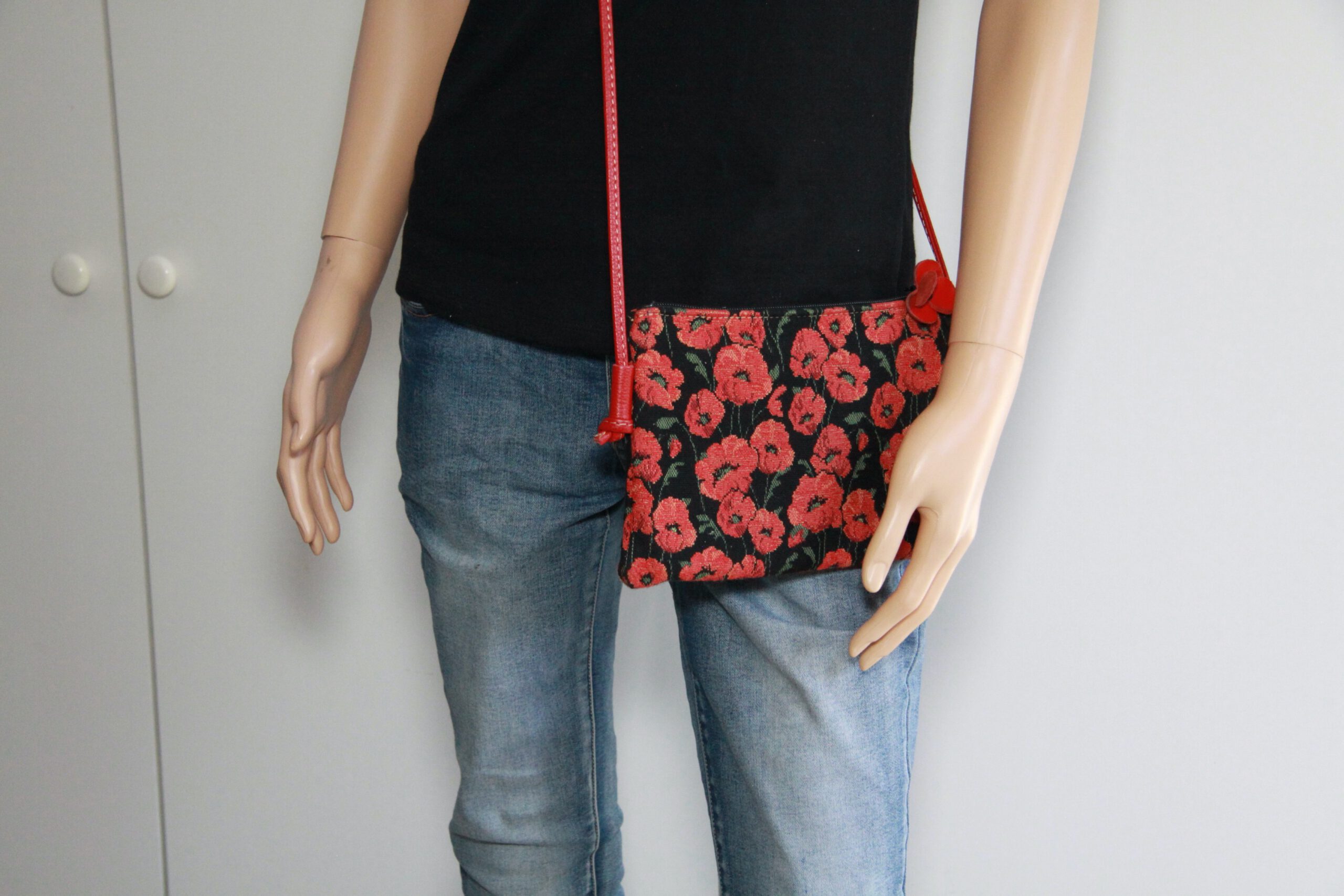 Sac à bandoulière en tissu jacquard, motif coquelicot rouge sur fond noir, présenté sur un mannequin.